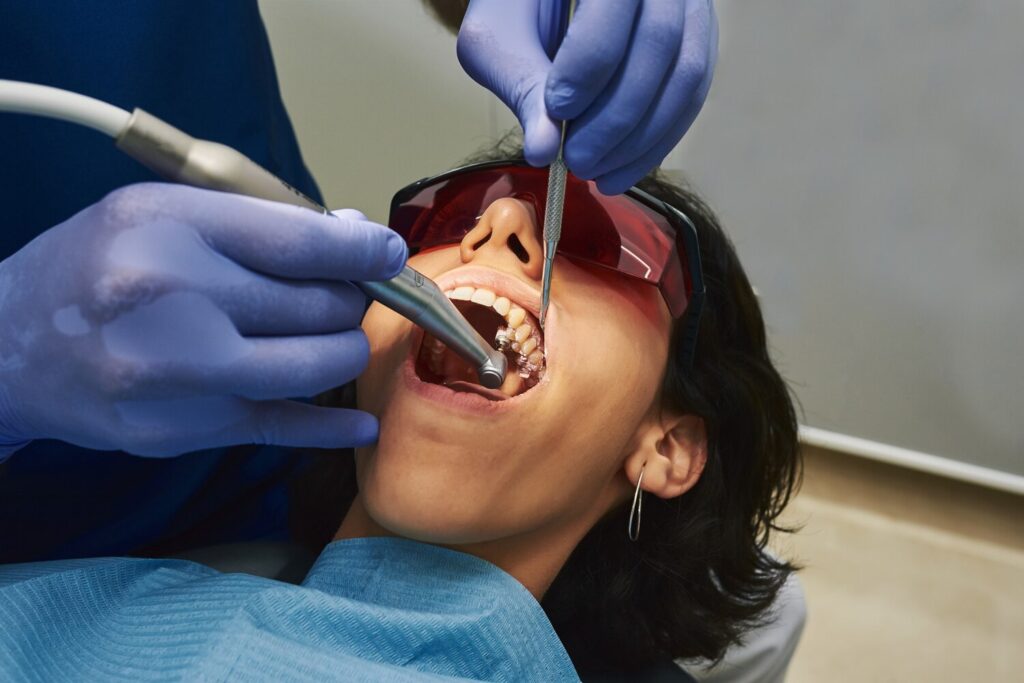 Dentist Cleaning Patient S Teeth She Is Wearing Red Goggles 230254 47